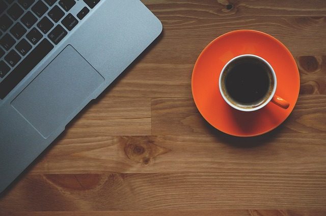 Un MacBook à côté d'une tasse de café