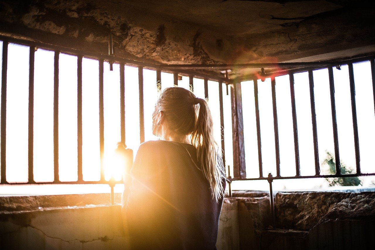 Une jeune femme attendant la fin du confinement devant sa fenêtre