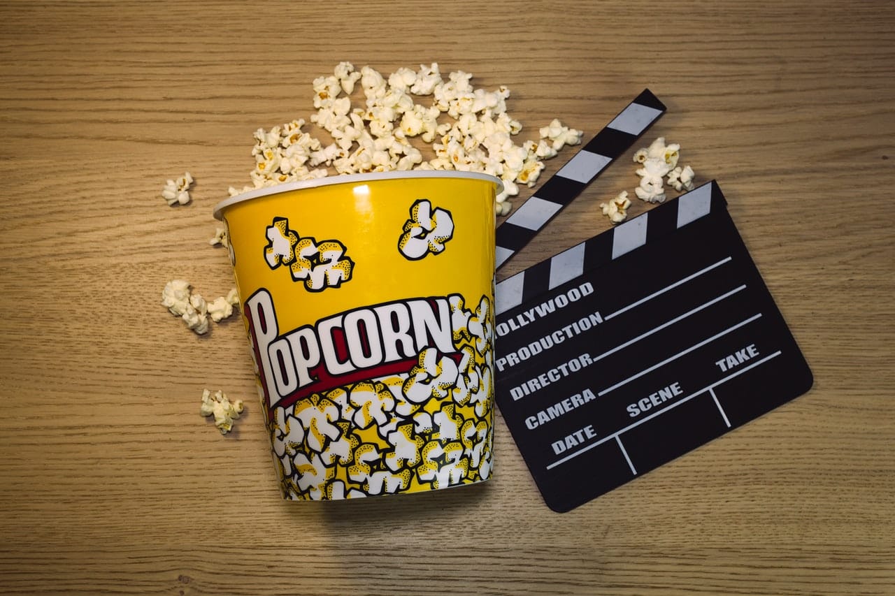 Un pot de popcorn à côté d'un clap de cinéma