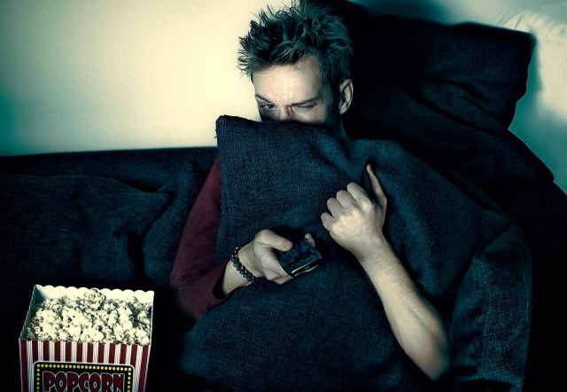 Un homme se cachant derrière un coussin