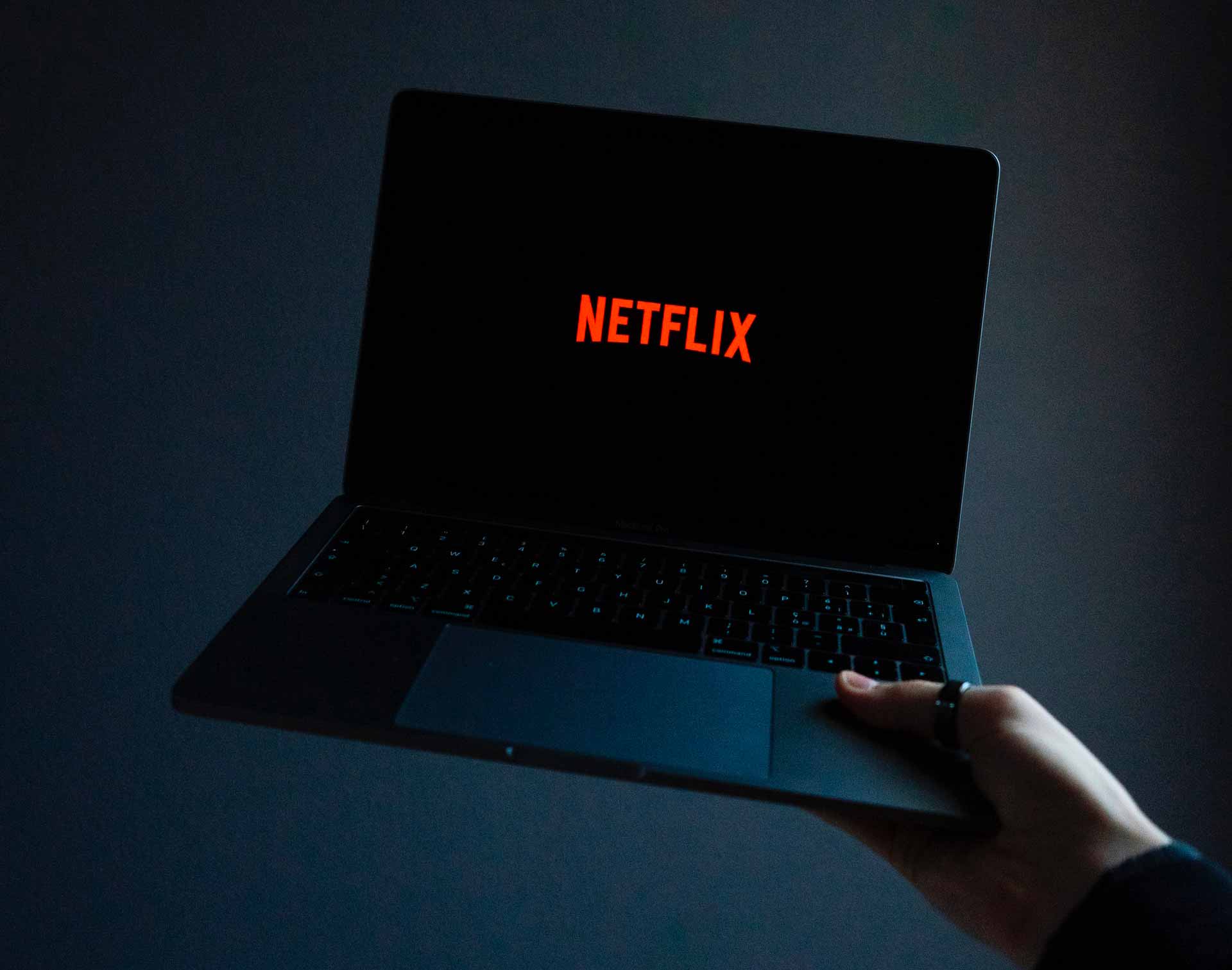 Netflix sur un ordinateur portable tenu à bras levé