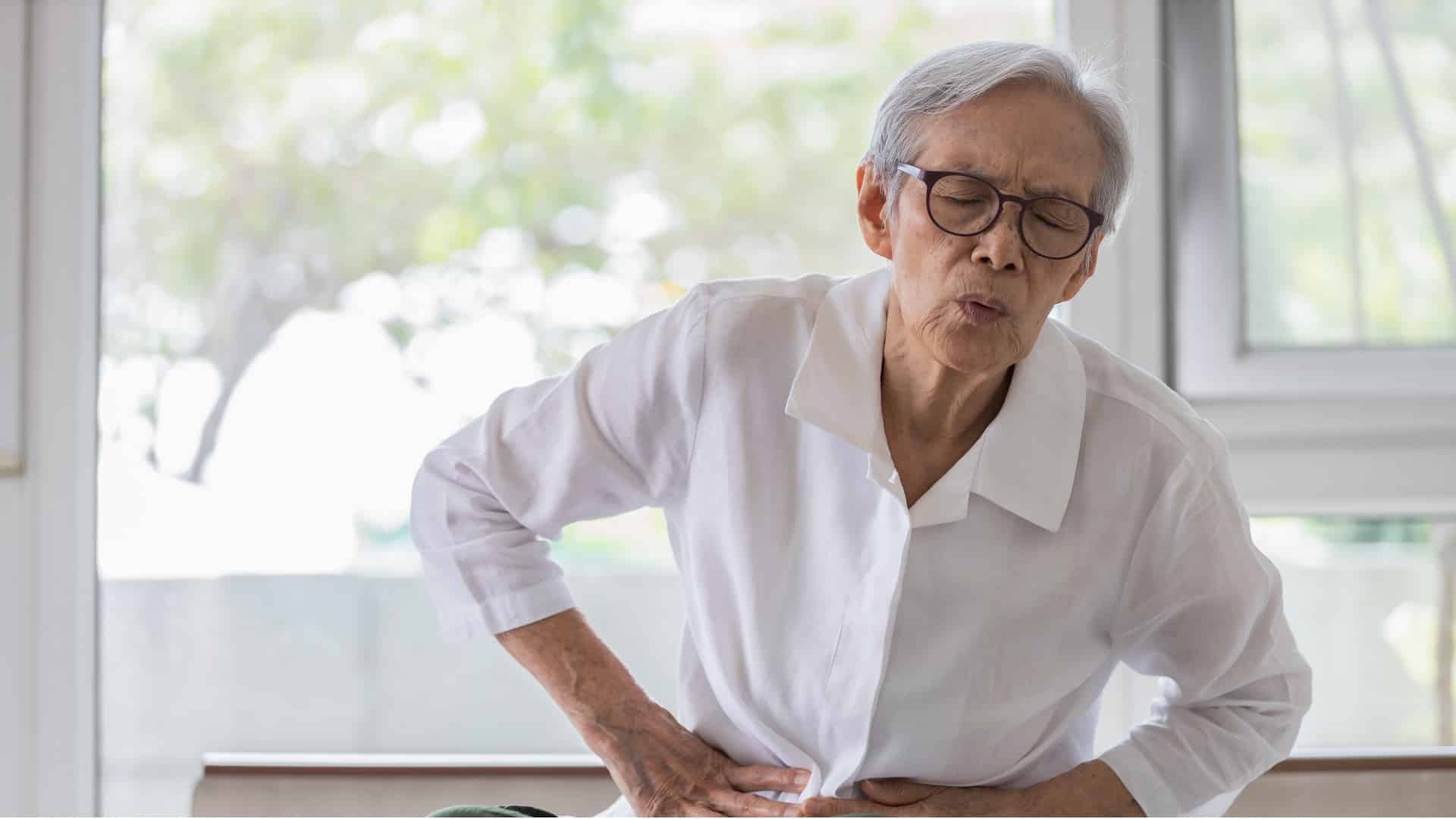 Un patient âgé atteint de gastro-entérite se tient le ventre et se tord de douleur.